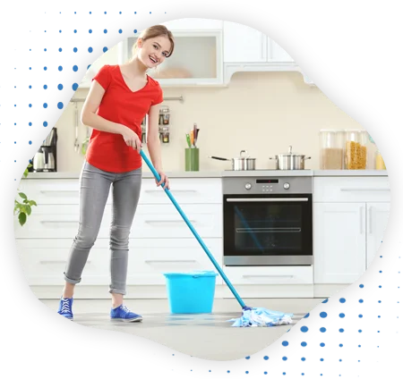 A lady mopping on floor in the kitchen premises